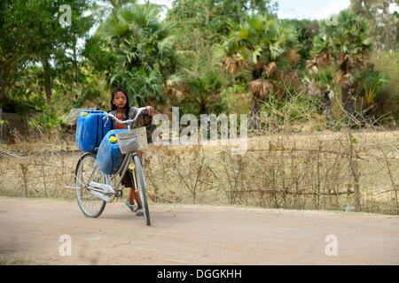 Mädchen, die Transport von zwei Kanister mit Wasser aus dem Reservoir der nahe gelegenen Pagode auf ihrem Fahrrad zu ihr nach Hause, Trapang Dorf Stockfoto