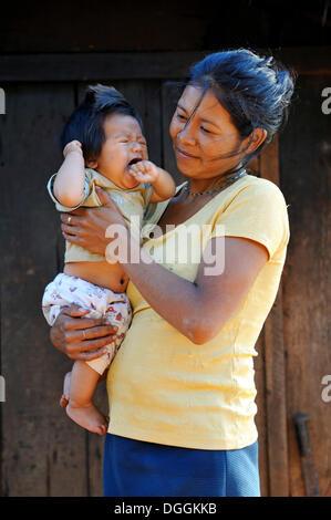 Junge Mutter hält ein weinendes Kind in die Arme, in einer Gemeinschaft von Guarani-Indianer, Jaguary, Caaguazu Abteilung, Paraguay Stockfoto