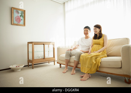 Mann und schwangere Frau sitzen auf sofa Stockfoto