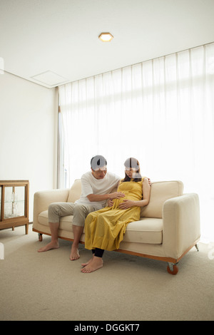 Mann rührende schwangeren Bauch auf sofa Stockfoto