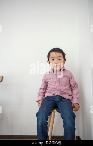 Junge sitzt auf Schemel, Porträt Stockfoto