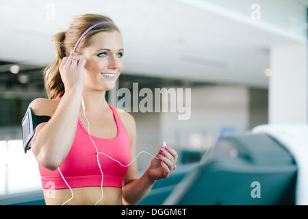 Junge Frau mit Smartphone-Armband und Ohrstöpsel Stockfoto