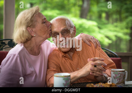 Ältere Frau küssen Mann, Lächeln Stockfoto