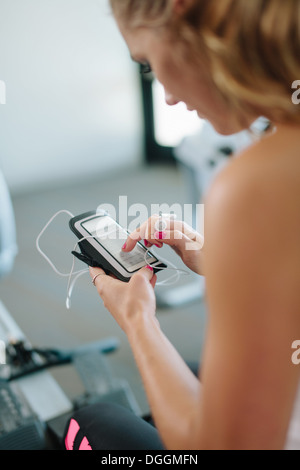 Junge Frau, mit mobilen während des Trainings im Fitnessstudio Stockfoto