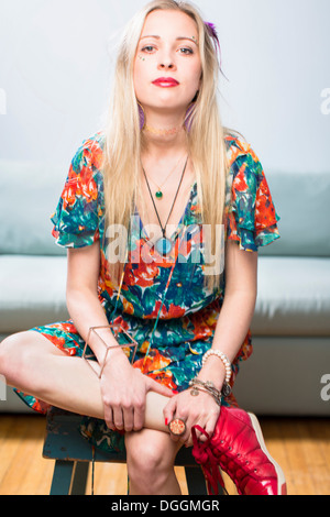 Junge Frau sitzt in floral gemusterten Kleid, Porträt Stockfoto