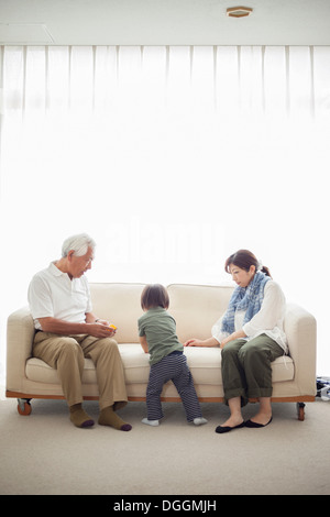 Junge mit seiner Mutter und Großvater auf sofa Stockfoto