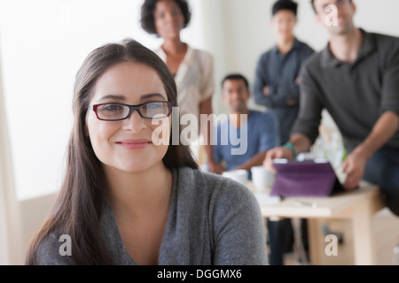 Porträt der jungen weiblichen Büroangestellten vor Kollegen Stockfoto