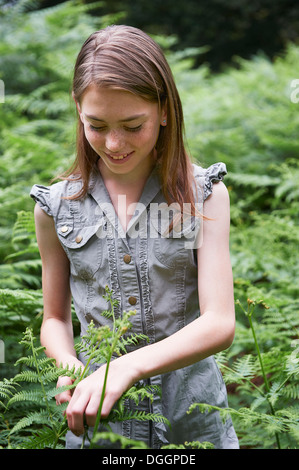 Teenager-Mädchen berühren Bracken im Wald Stockfoto