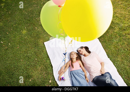 Mutter und Tochter auf Decke Holding Luftballons, hoher Winkel liegen Stockfoto