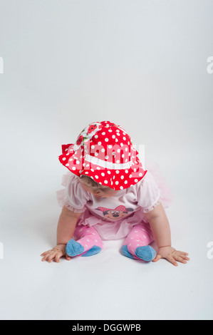 Babymädchen sitzen am Boden im niedlichen Pose tragen rot gepunkteten Hut Stockfoto