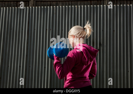 Junge Frau mit Hand Gewichte durch den Bau Stockfoto