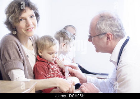 Kind auf Mutters Schoß von Arzt untersucht Stockfoto