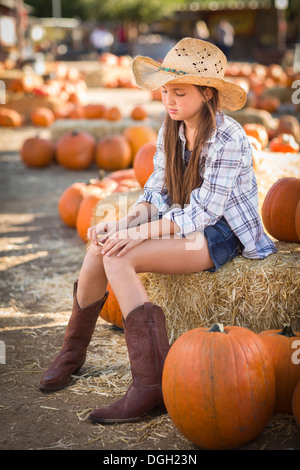 Preteen Mädchen tragen Cowboyhut Porträt im Kürbisbeet in rustikaler Umgebung. Stockfoto