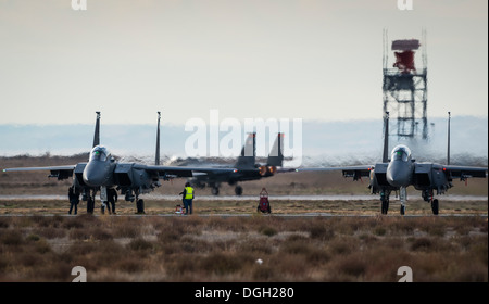 Wartungsteams führen letzten preflight Checklisten auf Republic of Singapore Air Force F-15SGs, während ein US Air Force F-15E Strike Eagle dahinter in Mountain Home Air Force Base, Idaho, 16. Oktober 2013 startet. Der Flug war Teil des Berges Roundup, Stockfoto