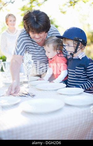 Jungen und Großmutter Einstellung Esstisch im freien Stockfoto