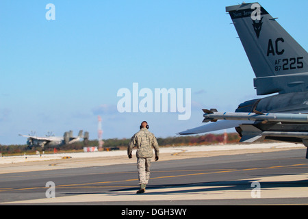 U.S. Air Force Airman First Class Alex Petrella hat einige Last-Minute-Prüfungen auf ein F - 16C Fighting Falcon von der New Jersey Air National Guard 177. Kämpfer-Flügel, wie eine US-Marine C-2A Greyhound von VAW-120 im Hintergrund am 18. Oktober im Atlantic landet Stockfoto