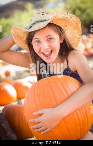 Preteen Mädchen hält einen großen Kürbis auf den Kürbis Patch in einem rustikalen Rahmen. Stockfoto