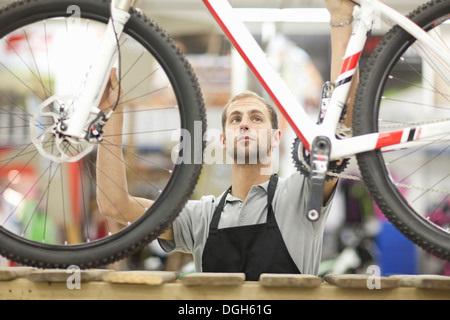 Junger Mann mit Fahrrad in Werkstatt Stockfoto