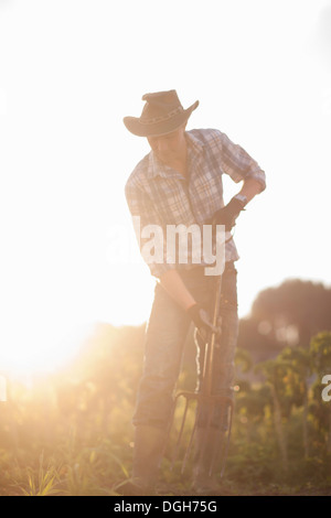 Junger Mann arbeitet auf Hof in der Sonne Stockfoto