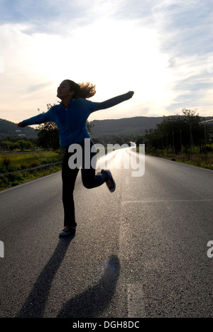 Junge Frau springen auf der Straße, in einen wunderschönen Sonnenuntergang, Ibiza, Spanien Stockfoto