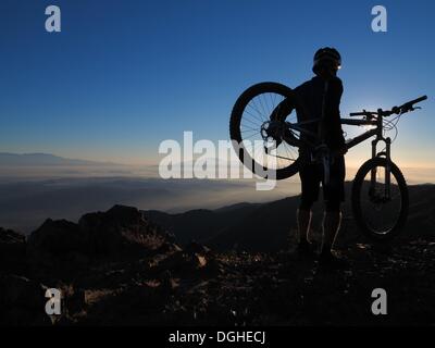 Modjeska Peak, Kalifornien, USA. 20. Oktober 2013. Mountainbiker BRIAN EPHRAIM klettert Modjeska Peak für Sunrise nach einer 5.000 ft hellen Mondnacht in Southern California Santa Ana Mountains. Mountainbiken ist der Sport der auf Fahrrädern abseits der Straße, oft über unebenes Gelände, mit speziell entwickelten Mountainbikes. Mountain-Bikes teilen Ähnlichkeiten mit anderen Bikes, sondern enthalten Funktionen, die Haltbarkeit und Leistung im Gelände zu verbessern. Diese einzelnen Sportart erfordert Ausdauer, Stärke und Balance, Fahrrad Umgang mit Fähigkeiten und Selbstvertrauen. Fortgeschrittene Radfahrer pur Stockfoto