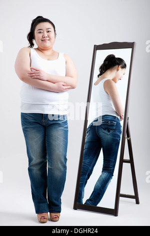 ein dickes Mädchen mit Jeans neben ein hoher Spiegel Stockfoto