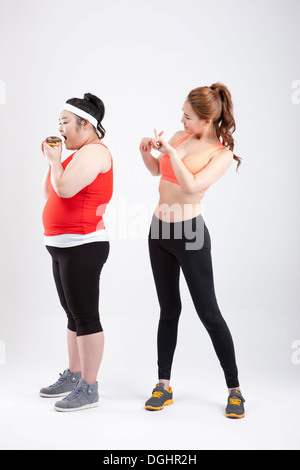 ein dickes Mädchen mit einem Donut und ein dünnes Mädchen in Sportkleidung Stockfoto