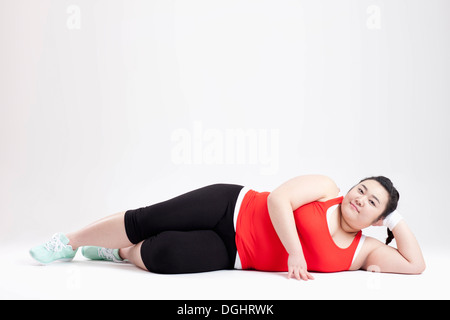 ein dickes Mädchen in einem Fitness-Studio-Outfit auf dem Boden liegend Stockfoto