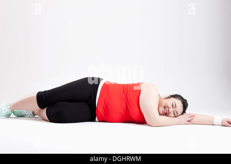 ein dickes Mädchen in einem Fitness-Studio-Outfit auf dem Boden liegend Stockfoto