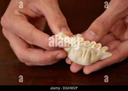 Hände, die hausgemachte Dim Sum asiatischen Knödel vorbereiten Stockfoto