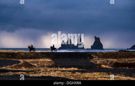 Zwei Horserider Reiten Islandpferde an der Küste, Reynisdrangar, schwarzer Basalt Meer Stapeln, Reynisdrangar, Vík Í Mýrdal Stockfoto