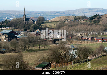 St. Thomas Kirche über das Beal Tal, Newhey, Rochdale, Greater Manchester, England, UK.  Metrolink Straßenbahn im Vordergrund. Stockfoto