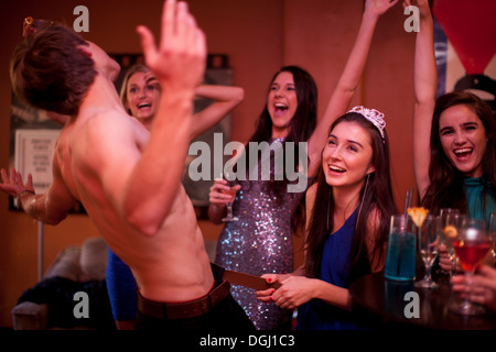 Junge Frauen beobachten männliche Arbeitswalze am Junggesellinnenabschied Stockfoto