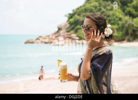 Frau mit Handy am Strand, dieser Tree Resort, Ko Samui, Thailand Stockfoto