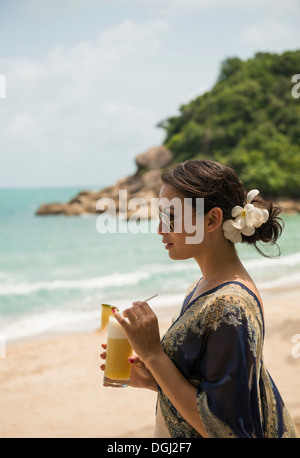 Frau mit Getränk am Strand, dieser Tree Resort, Ko Samui, Thailand Stockfoto