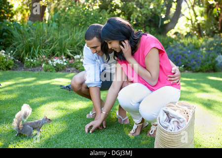 Junges Paar beobachten Eichhörnchen im Garten Stockfoto