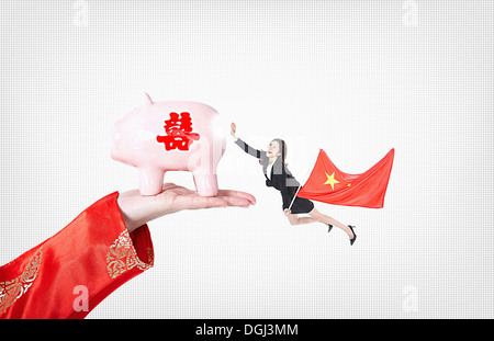 eine Geschäftsfrau mit einer Fahne von Chine hält ein Sparschwein Stockfoto