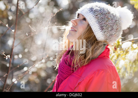 Junge Frau unter schneebedeckten Äste Stockfoto