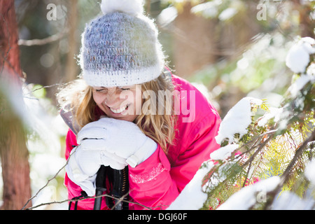 Junge Frau unter schneebedeckten Äste Stockfoto