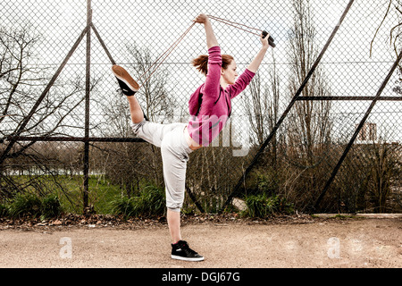 Frau in Hoodie Pilates Seil von hinten gebogenen Bein ziehen Stockfoto