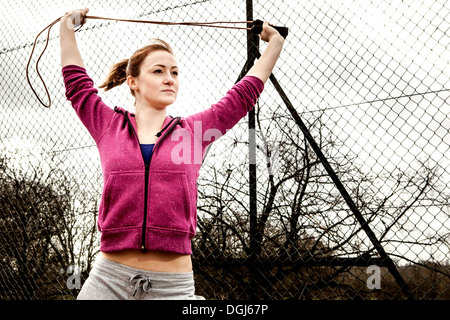 Frau in Hoodie Dehnung Pilates Seil über Kopf Stockfoto