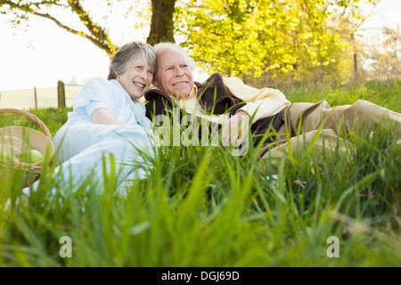 Älteres paar entspannende und Picknick auf Feld Stockfoto