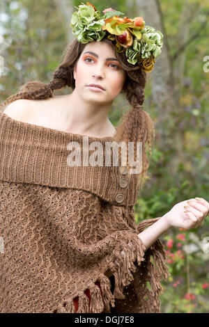 Junge Frau trägt einen braunen Poncho mit einem flowal Kranz im Haar, im freien Stockfoto