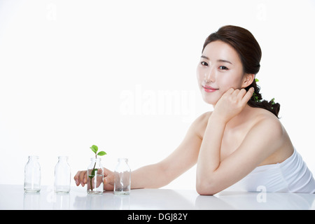 eine Frau posiert mit einem Blatt in einer Glasvase Stockfoto