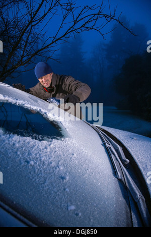 Mann von Frost bedeckt Auto Windschutzscheibe kratzen Eis. Stockfoto