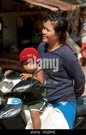 Frau und Kind mit Nike Hut auf einem Motorrad, Battambang, Kambodscha, Südost-Asien Stockfoto