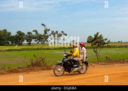 Zwei Frauen reiten auf einem Motorrad auf einer Landstraße, Kambodscha Stockfoto