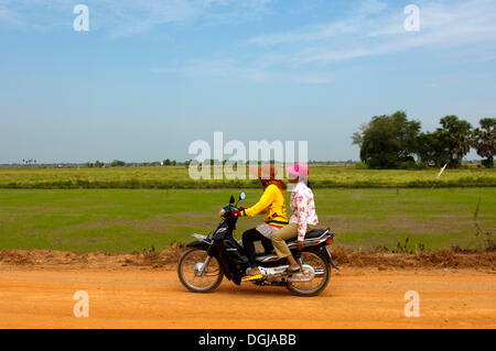 Zwei Frauen reiten auf einem Motorrad auf einer Landstraße, Kambodscha Stockfoto