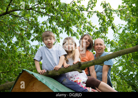 Familie mit zwei Kindern auf Spielhaus Dach sitzt Stockfoto