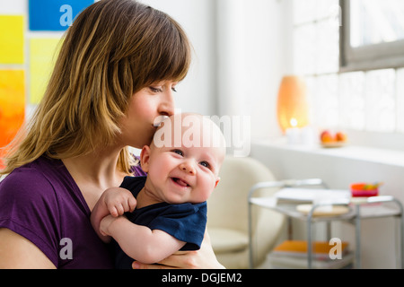 Mutter küssen Baby Sohn auf Kopf Stockfoto